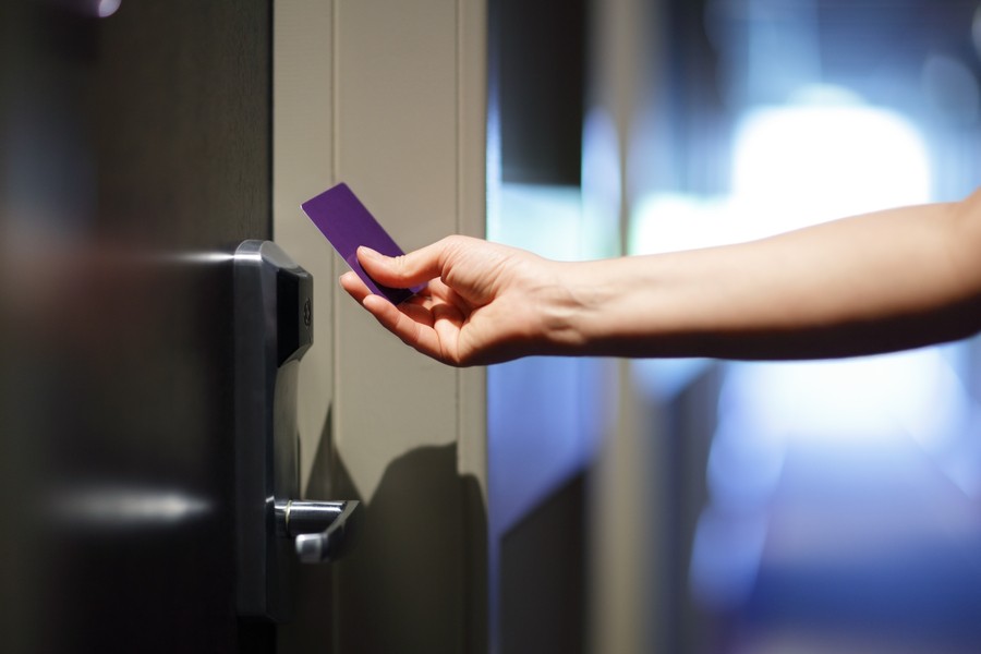 Hand holding an ID card to an access control reader.