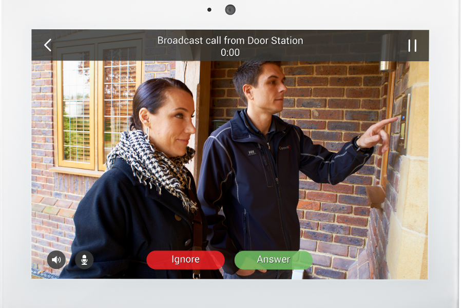 A man and woman stand together in front of a door using a home intercom system. 