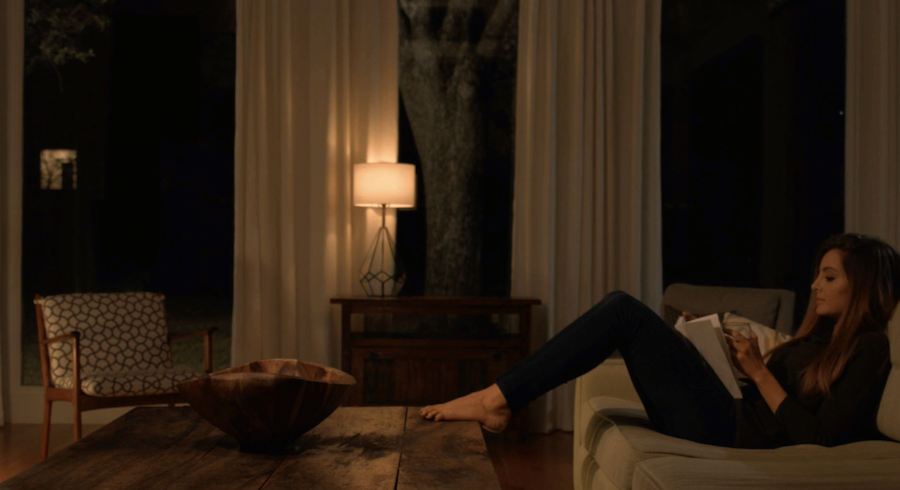 A woman reads a book in a dimly lit room.