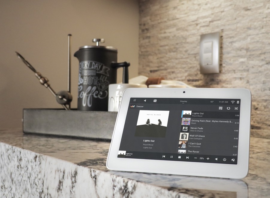 A Control4 tablet sits on a marble counter. It is playing the song Lights Out through the Deezer app.