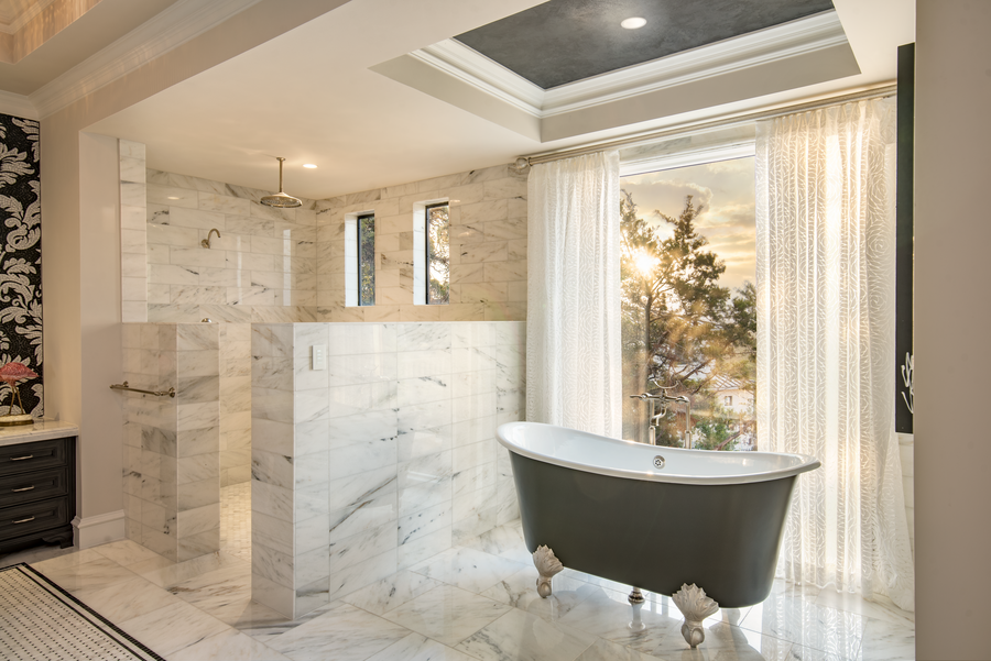 A marble bathroom with an elegant tub and shower illuminated by Ketra lighting. 