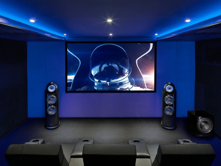 Bowers & Wilkens speakers frame a home theater design with custom seating bathed in blue illumination. 